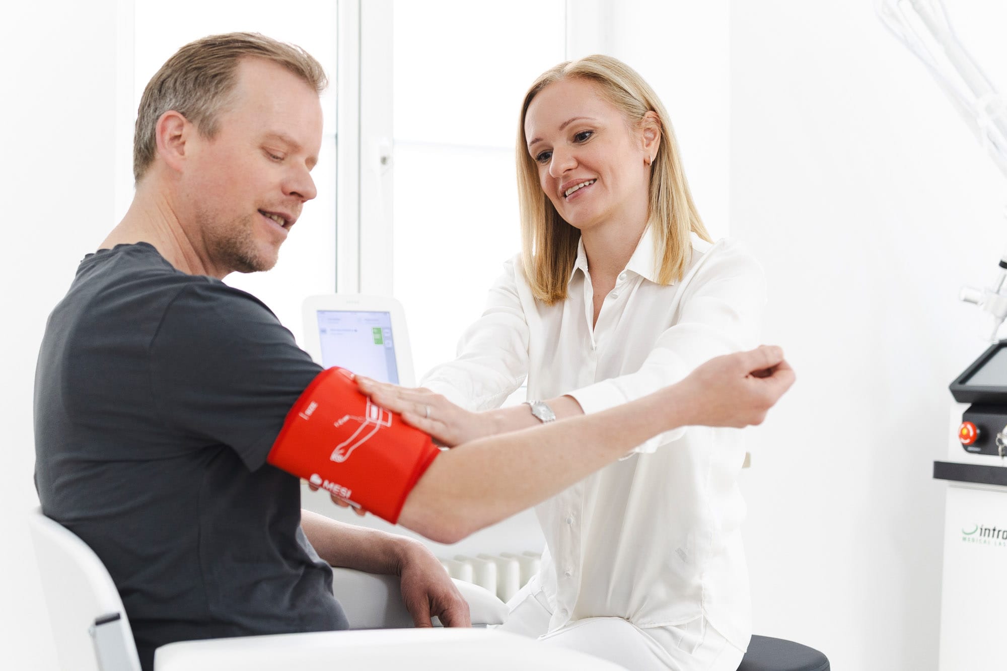Dr. Madalina Werneke legt einem Patienten eine Manschette für eine digitale Blutdruckmessung an.